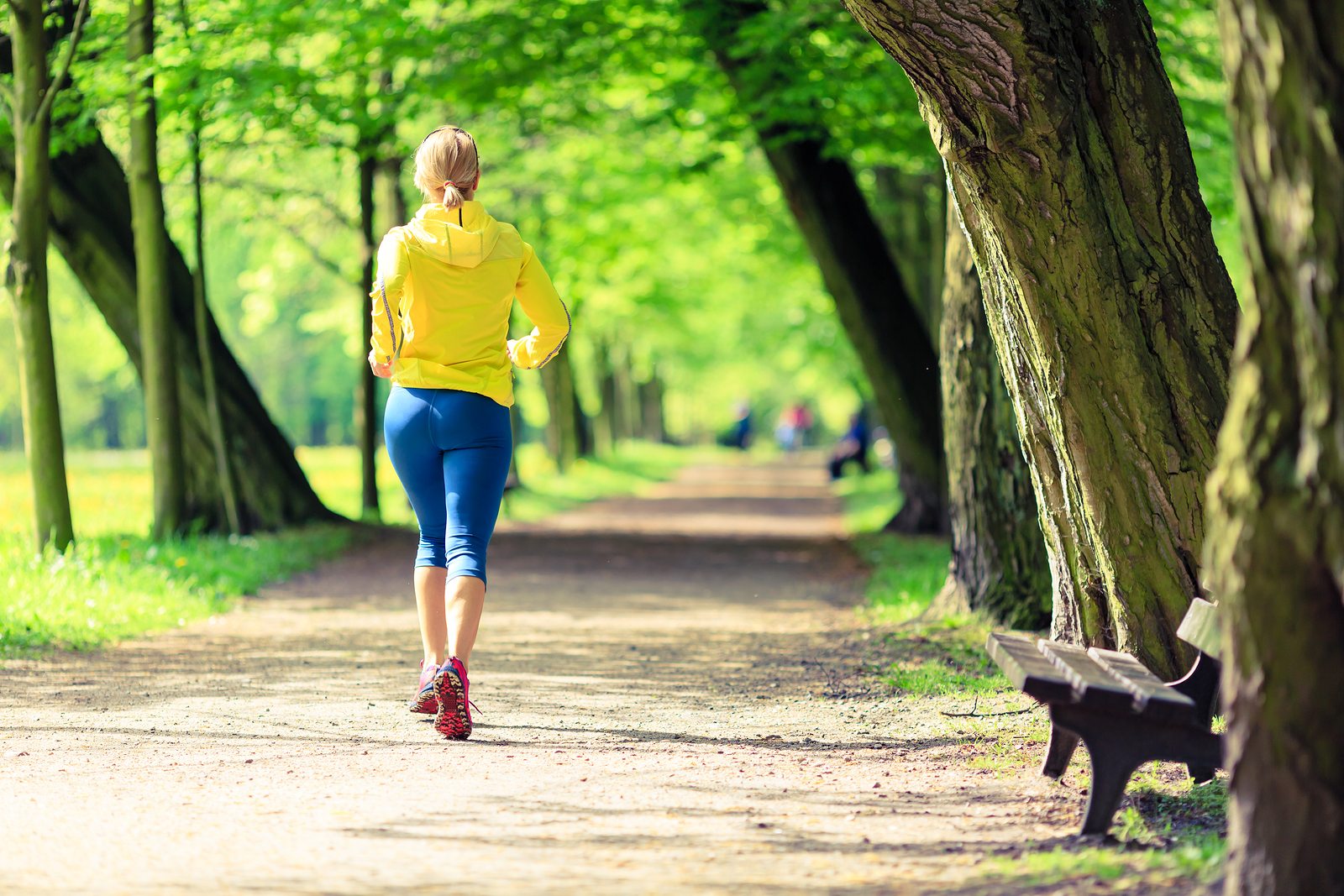 Woman running and walking in beautiful city park. Young girl jogging in bright forest outdoors summer nature. Endurance concept with working out and exercising in inspirational green woods landscape.