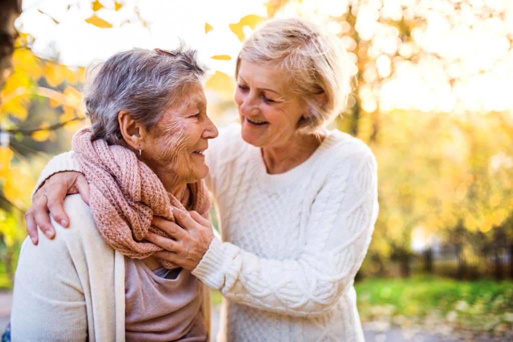 Senior women on a walk in autumn nature. An elderly woman with her senior daughter walking outside.