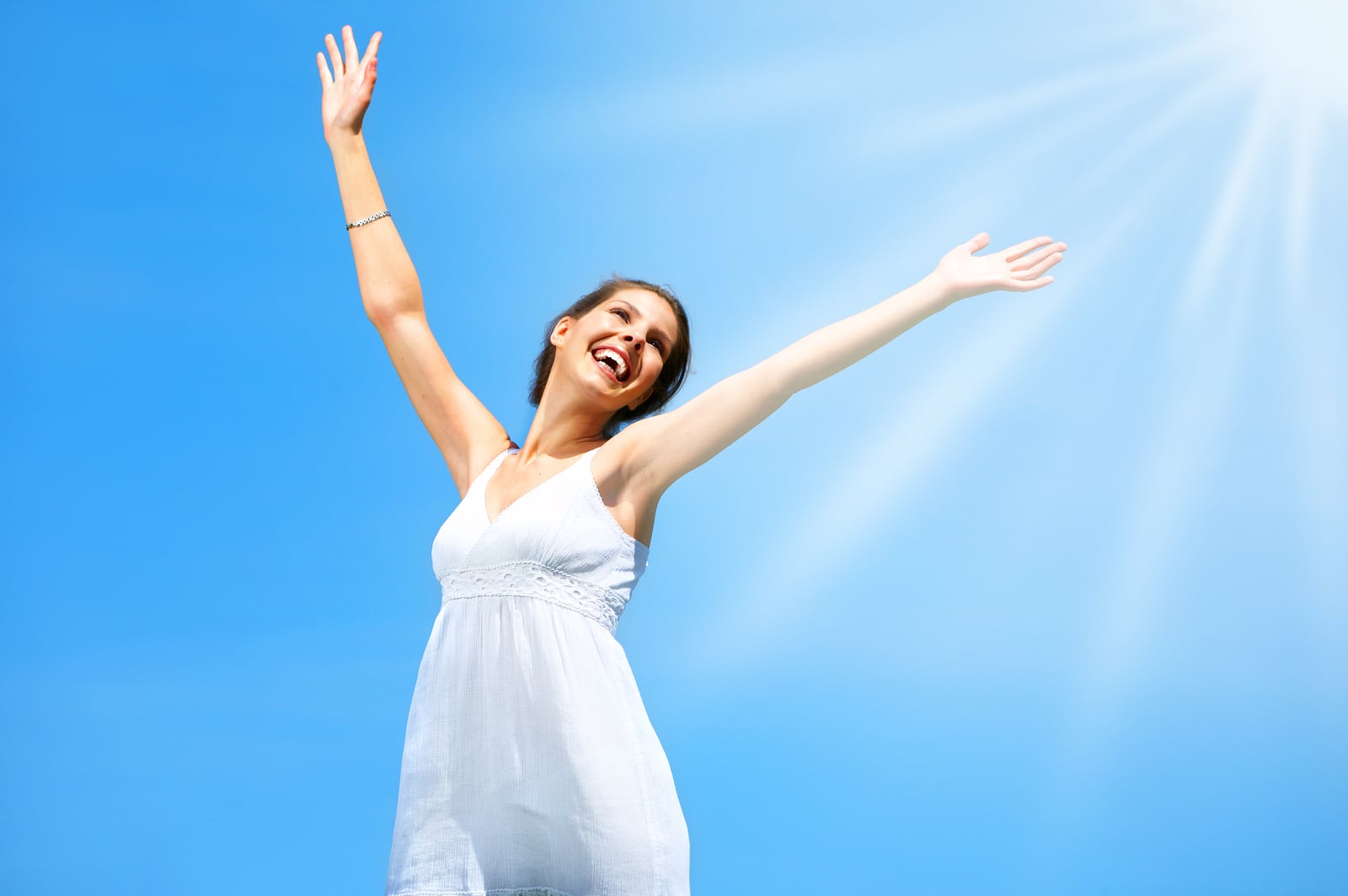 happy girl with arms up and a blue sky