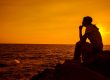 Silhouette women sitting alone on the rock. Mental health, PTSD and suicide prevention.