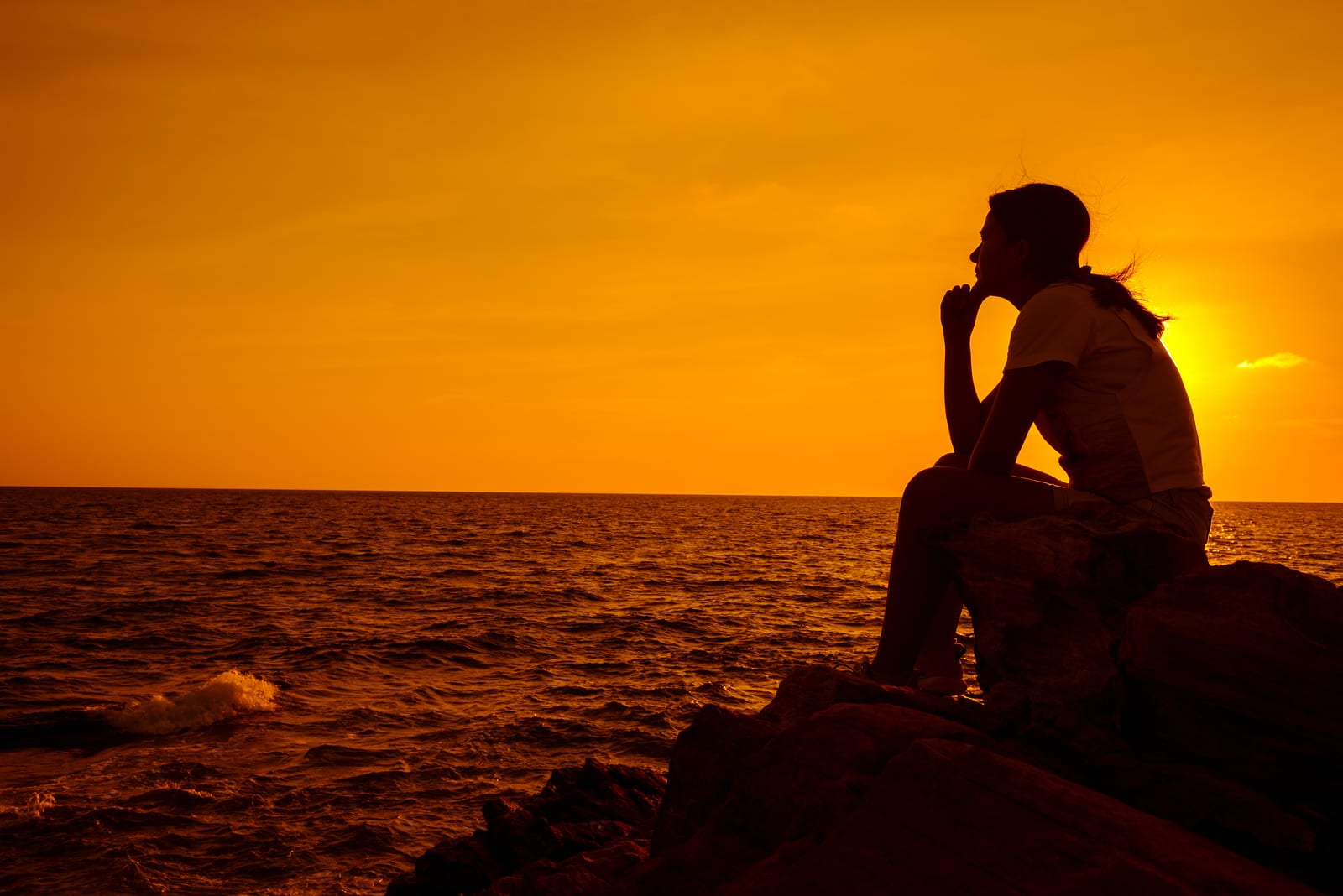 Silhouette women sitting alone on the rock. Mental health, PTSD and suicide prevention.