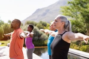 Group of senior people with closed eyes stretching arms outdoor.