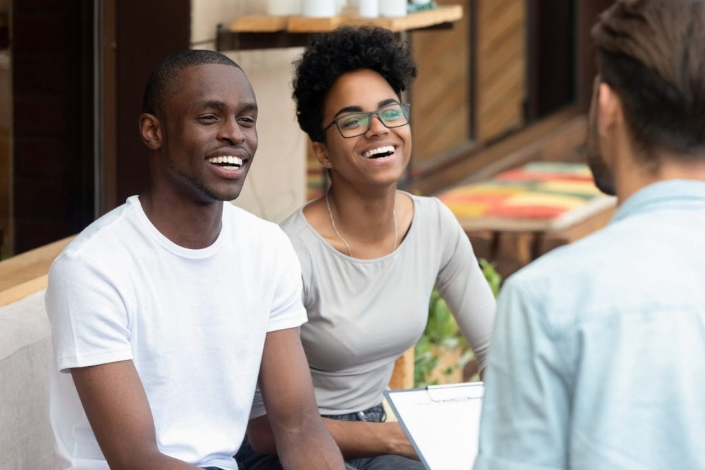 Happy couple talking with person with clipboard