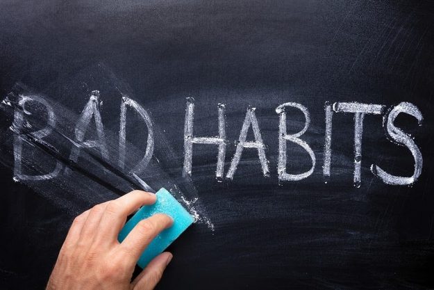 Person Erasing "Bad Habits" on Chalkboard